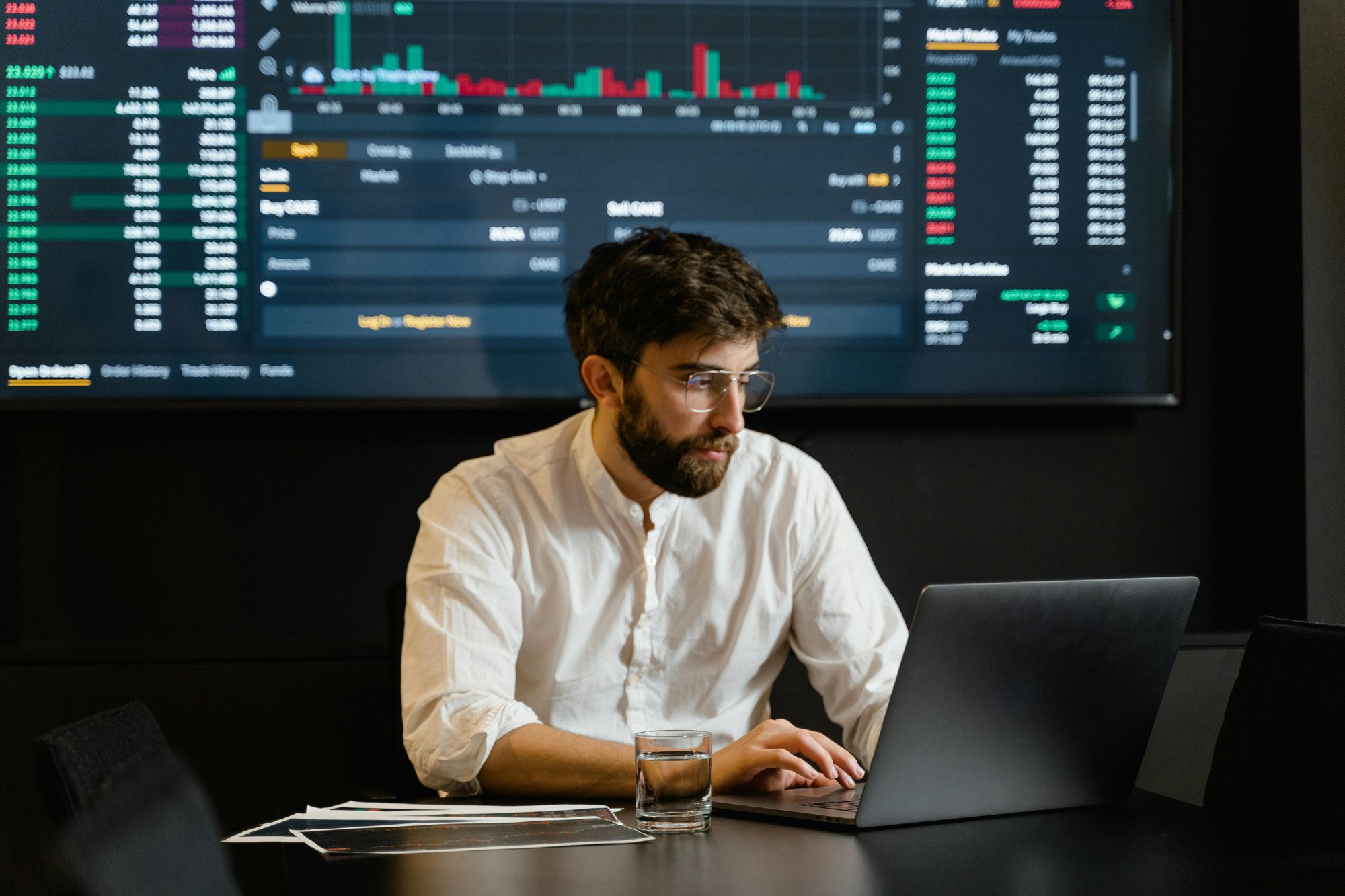 man working on computer in front of screen full of data