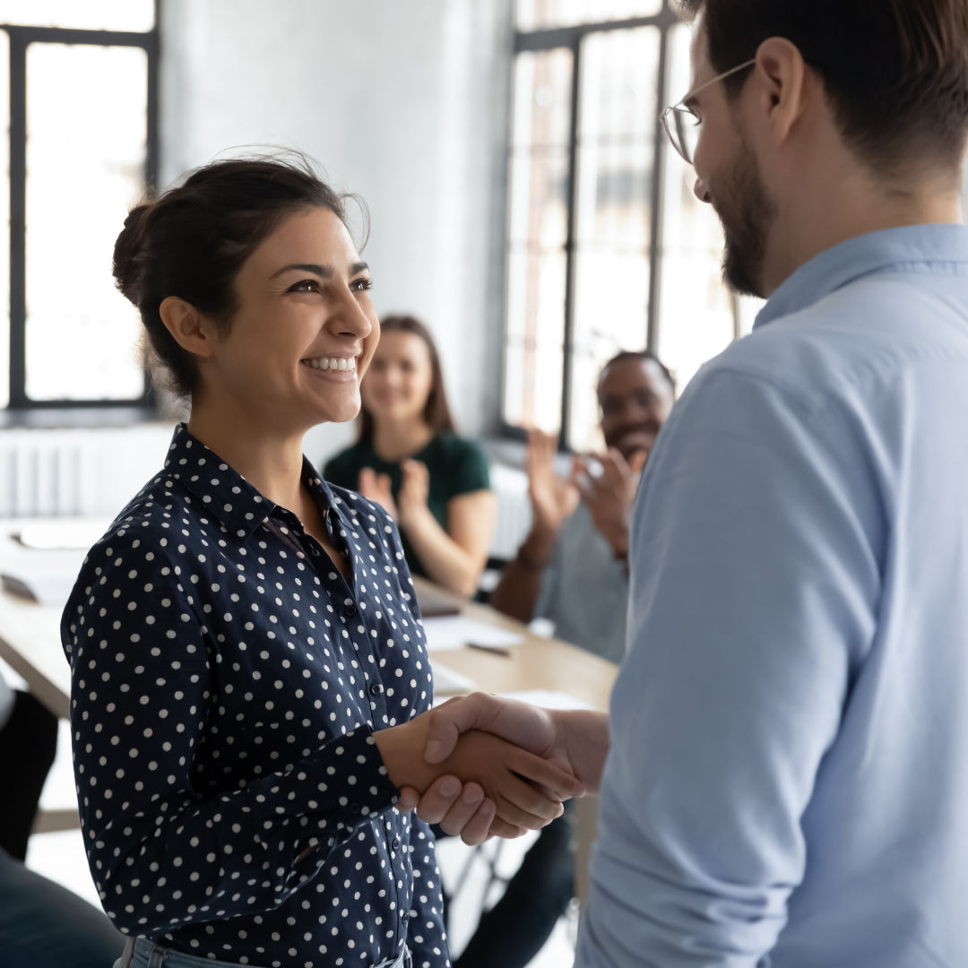 Women shakes a mans hand accepting a promotion